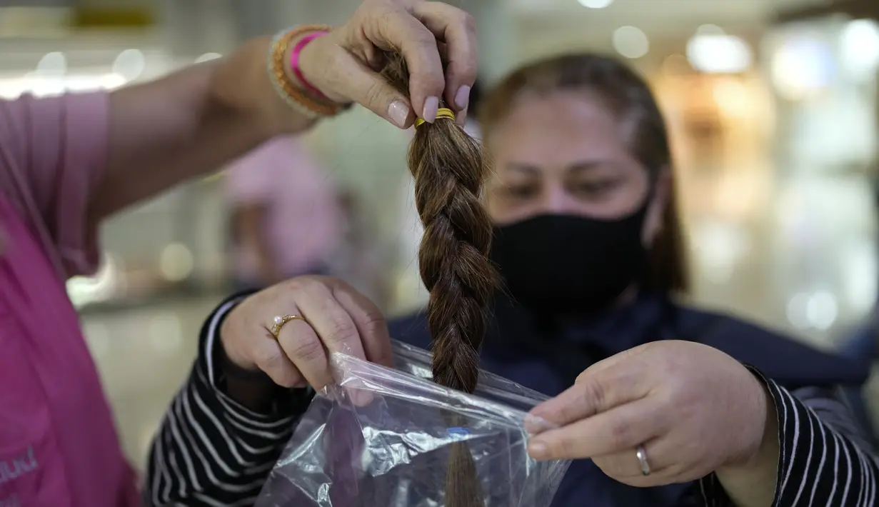 Bagian rambut Iliana Maluenga dimasukkan ke dalam kantong plastik setelah dipotong dalam acara Bulan Peduli Kanker Payudara di sebuah mal di Caracas, Venezuela, Sabtu (16/10/2021). Rambut yang dipotong akan disumbangkan untuk membuat wig bagi pasien kanker. (AP Photo/Ariana Cubillos)