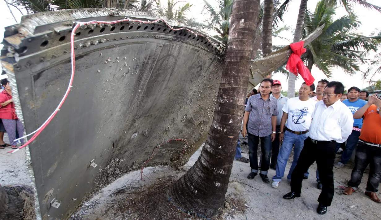 Warga mengamati potongan pesawat yang ditemukan di pantai Thailand selatan, Minggu (24/1). Serpihan besar berupa kepingan logam melengkung yang diduga dari pesawat Malaysia Airlines MH370 terdampar di Nakhon Si Thammarat. (REUTERS/Surapan Boonthanom)