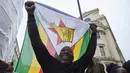 Demonstran membawa bendera nasional Zimbabwe dalam aksi protes di luar Kedutaan Besar Zimbabwe di London, Sabtu (18/11). Komunitas warga Zimbabwe menggelar aksi long march menyerukan teriakan agar Presiden Robert Mugabe mundur. (NIKLAS HALLE'N/AFP)