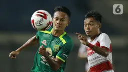 Pemain Persebaya Surabaya, Koko Ari (kiri), berebut bola dengan pemain Madura United, Mochamad Kevy, pada laga Piala Menpora 2021 di Stadion Si Jalak Harupat, Bandung, Minggu (28/3/2021). Persebaya Surabaya menang 2-1. (Bola.com/M Iqbal Ichsan)