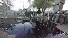 Petugas polisi dan awak media berkumpul di lokasi penyerbuan mematikan di pusat distribusi makanan dan sedekah Ramadhan di kota pelabuhan Karachi, Pakistan selatan, Jumat, 31 Maret 2023. (AP Photo/Fareed Khan)