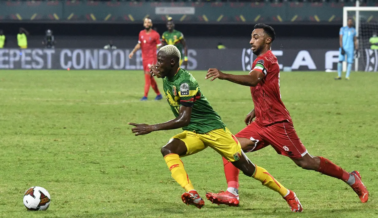 Gelandang Mali Moussa Djenepo (kiri) berebut bola dengan bek Guinea Khatulistiwa Carlos Akapo pada babak 16 besar Piala Afrika 2021 di Stadion Limbe, Kamis (27/1/2022) dini hari WIB. Guinea Ekuatorial mempermalukan Timnas Mali 6-5 (0-0) dalam adu penalti. (Issouf SANOGO/AFP)