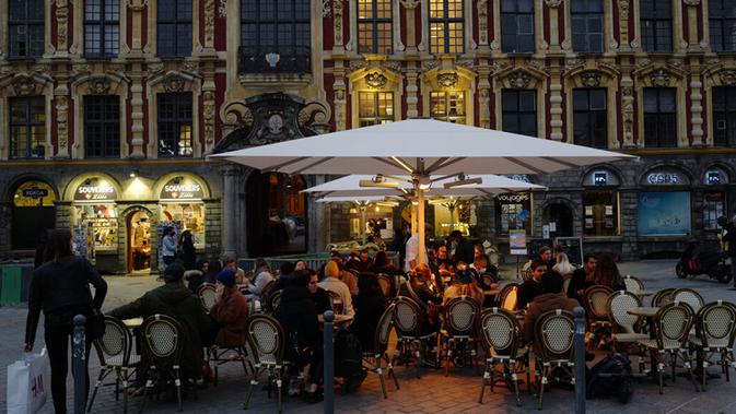 Orang-orang menikmati makanan di Lille, Prancis, Jumat (16/10/2020). Prancis mengerahkan 12.000 polisi untuk memberlakukan jam malam baru mulai Jumat malam hingga bulan depan untuk memperlambat penyebaran COVID-19. (AP Photo/Michel Spingler)