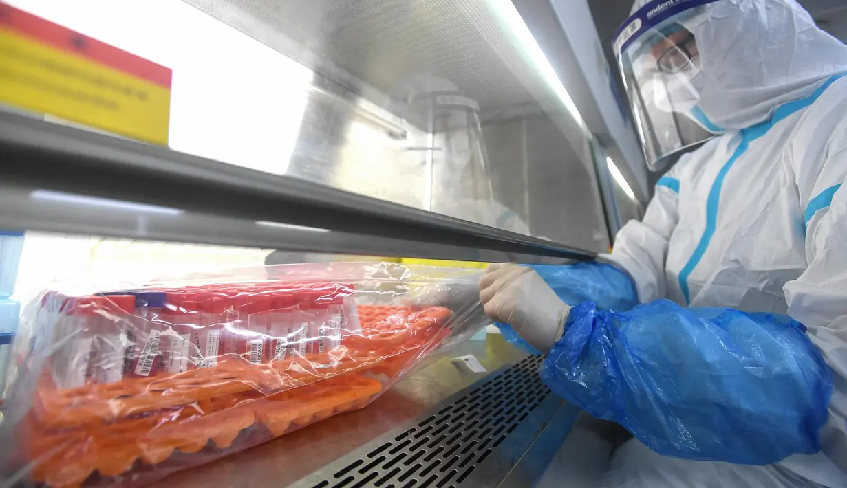Seorang teknisi laboratorium yang mengenakan alat pelindung diri (APD) bekerja pada sampel yang akan diuji untuk virus corona Covid-19 di laboratorium Mata Api, fasilitas pengujian Covid-19, di Wuhan di provinsi Hubei tengah China (5/8/2021). (AFP/STR)