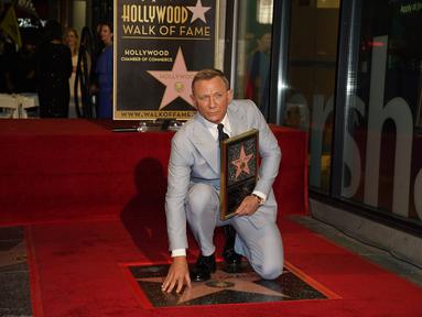 Daniel Craig berpose di atas bintang barunya di Hollywood Walk of Fame pada upacara penghargaan di Los Angeles, Rabu (6/10/2021). Nama Daniel Craig di Hollywood Walk of Fame diletakkan di samping aktor Roger Moore, pemeran James Bond terdahulu. (AP Photo/Chris Pizzello)