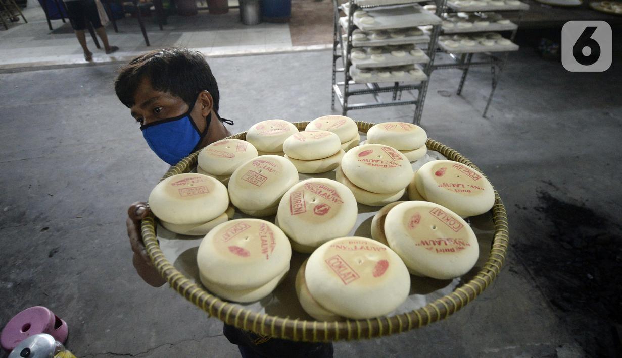 Pekerja membawa kue bulan di Industri Rumahan Kue Bulan Putri Lauw, Pondok Sentul, Ciater, Tangerang Selatan, Selasa (10/11/2020). Pada masa pandemi sekarang, produksi kue tradisional khas Tionghoa tersebut menurun sesuai pesanan pembeli. (merdeka.com/Dwi Narwoko)