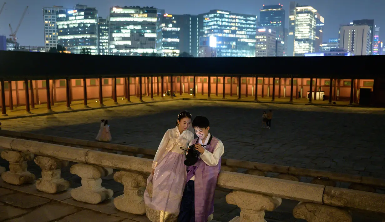 Gambar pada 4 Oktober 2019, wisatawan memainkan kamera mereka saat kunjungan malam ke Istana Gyeongbokgung di pusat Seoul, Korea Selatan. Kunjungan malam tersedia pada minggu ketiga dan keempat setiap bulan mulai dari 26 April sampai 31 Oktober, kecuali pada bulan Agustus. (Photo by Ed JONES / AFP)