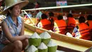 Pedagang kelapa menunggu pembeli di pasar terapung Damnoen Saduak, Bangkok, Thailand, Jumat (21/6/2019). Selain buah-buahan, pedagang pasar terapung Damnoen Saduak juga menjual sayur, makanan hingga oleh-oleh. (TANG CHHIN Sothy/AFP)