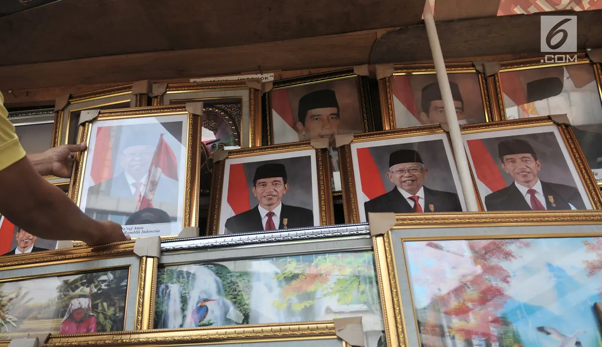 Pedagang merapikan foto Presiden-Wapres 2019-2024, Joko Widodo-KH Ma'ruf Amin di salah satu toko di Pasar Baru, Jakarta, Senin (26/8/2019). Meski belum resmi dilantik, foto Presiden dan Wakil Presiden Terpilih Joko Widodo-KH Ma'ruf Amin telah beredar di pasaran. (merdeka.com/Iqbal S. Nugroho)