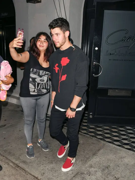 Nah ini ketika Nick Jonas melayani fans untuk foto bareng saat jalan-jalan. (Getty Images/USWeekly)