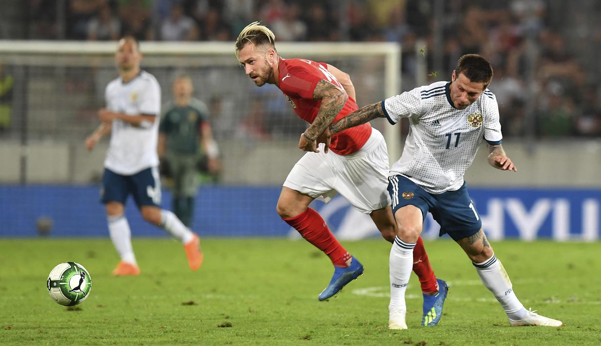 Pemain Austria, Peter Zulj (kiri) berebut bola dengan pemain Rusia, Fedor Smolov pada laga uji coba di Tivoli Stadium, Innsbruck, Austria, (30/5/2018). Austria menang atas Rusia 1-0. (AP/Kerstin Joensson)