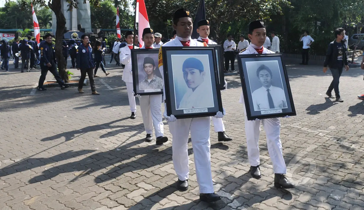 Mahasiswa berjalan sambil memegang foto aktivis yang tewas saat menggelar aksi peringatan 'Tragedi Trisakti 12 Mei 1998' di Universitas Trisakti, Jakarta, Selasa (12/5/2015). (Liputan6.com/Johan Tallo)