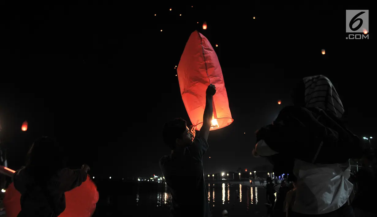 Pengunjung menerbangkan lampion saat perayaan Tahun Baru Imlek di Pantai Lagoon, Ancol, Jakarta, Selasa (5/2) malam. Sebanyak 500 lampion diterbangkan oleh pengunjung dalam  rangka menutup Festival Imlek di Ancol. (Merdeka.com/Iqbal S Nugroho)