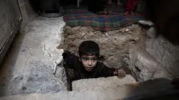 Seorang bocah berada di lubang menuju ruang bawah tanah Abu Omar di Douma, Damaskus, Suriah, (30/10). Abu Omar dibantu tetangganya berhasil menggali dan membangun ruangan di kedalaman 4 meter dari permukaan tanah. (AFP PHOTO/Sameer Al-Doumy)