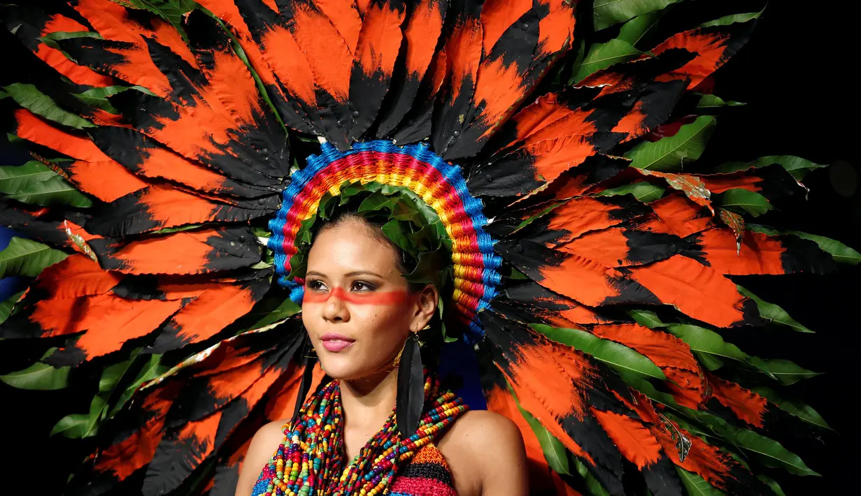 Seorang model berpose di atas catwalk mengenakan busana yang berwarna-warni lengkap dengan aksesoris kepala yang terbuat dari rangkaian dedaunan saat pergelaran Biofashion di Cali, Kolombia (19/11). (Reuters/Jaime Saldarriaga)