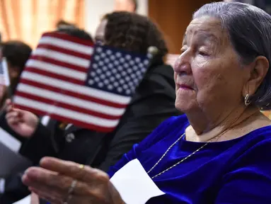 Maria Valles Bonilla melambaikan bendera AS selama upacara naturalisasi di kantor Citizenship and Immigration Services AS (USCIS) di Fairfax, Virginia, 6 November 2018. Nenek 106 tahun itu resmi menjadi warga negara Amerika Serikat. (MANDEL NGAN/AFP)