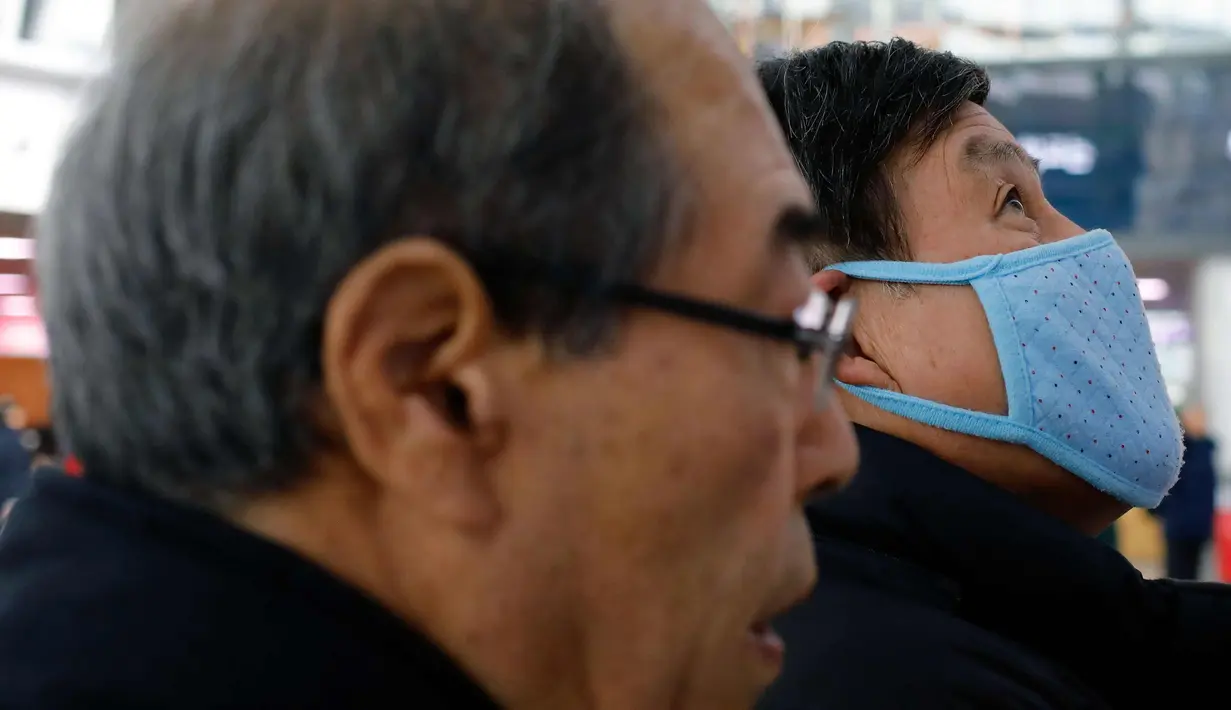 Seorang pria mengenakan masker melihat jadwal kereta di Stasiun Seoul di Seoul, Korea Selatan (19/2). (AFP Photo/David Gannon)