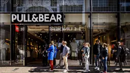 Pelanggan menunggu dalam antrean di depan toko pakaian Pull & Bear yang dibuka kembali di shopping street di Amsterdam, Rabu (28/4/2021). Belanda mulai melonggarkan pembatasan ketat terkait Covid-19, mengakhiri jam malam dan mengizinkan kafe untuk buka di luar ruangan. (REMKO DE WAAL/ANP/AFP)