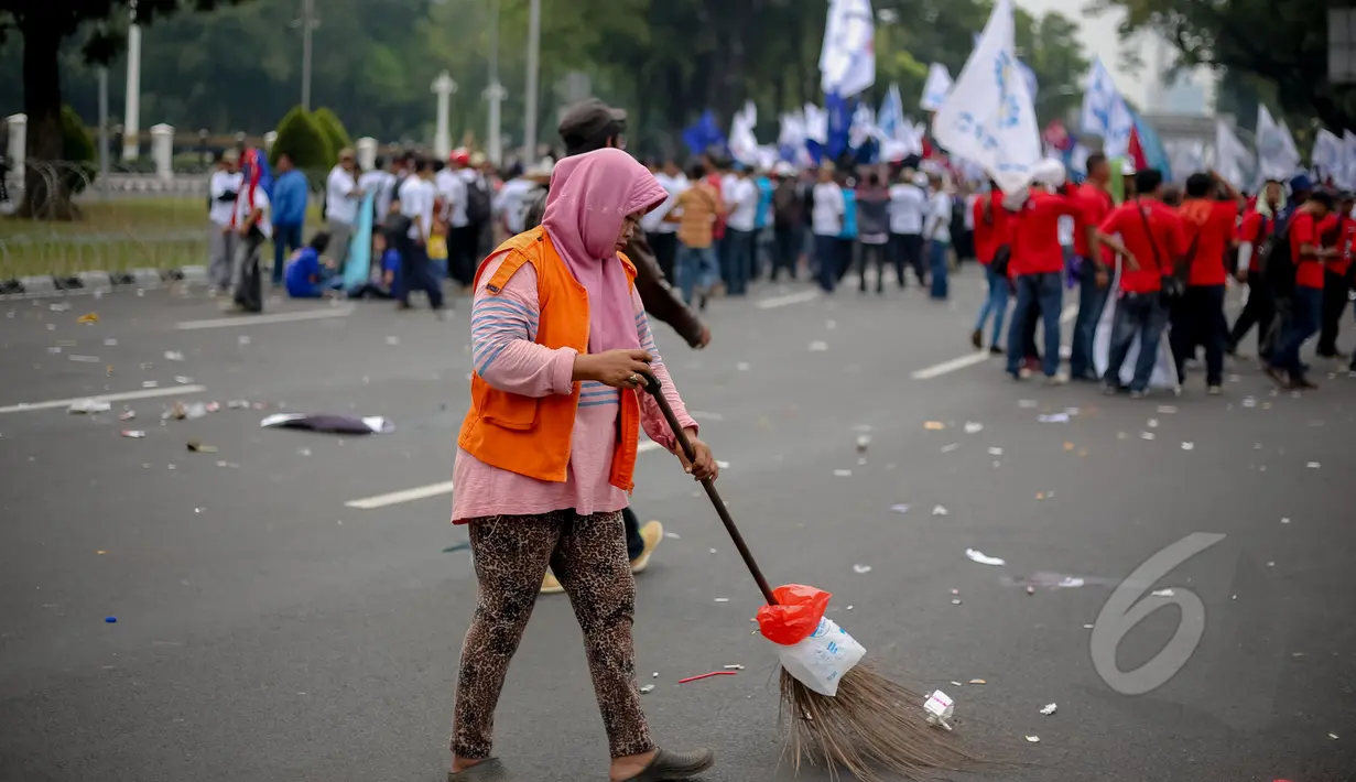 Petugas kebersihan membersihkan sampah saat peringatan hari buruh sedunia yang jatuh pada tanggal 1 Mei di depan Istana Merdeka, Jakarta, Jumat (1/5/2015). Aksi demo May Day menyisahkan sejumlah sampah berserakan di jalan. (Liputan6.com/Faizal Fanani)