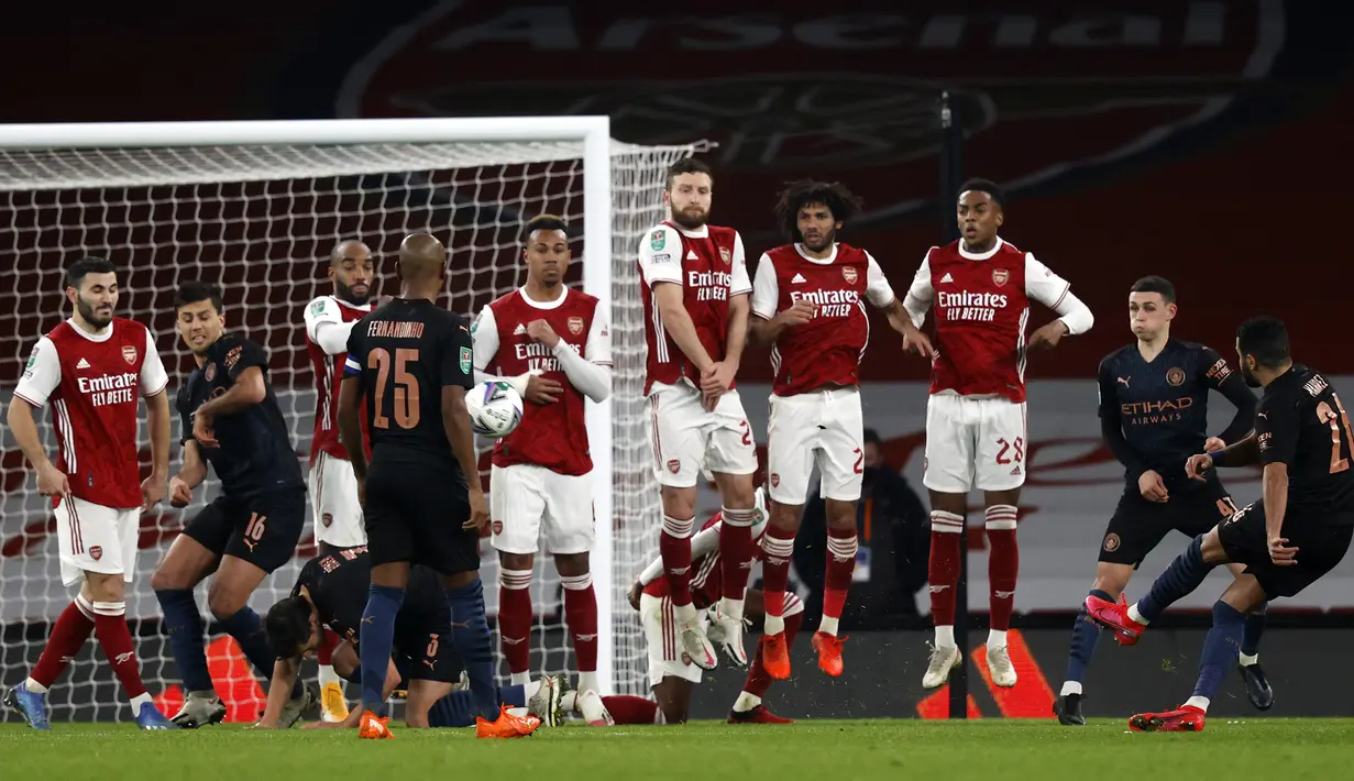 Gelandang Manchester City, Riyad Mahrez (kanan), mencetak gol kedua timnya lewat tendangan bebas ke gawang Arsenal dalam laga perempatfinal Piala Liga Inggris Carabao Cup di Emirates Stadium, London, Selasa (22/12/2020). Manchester City menang 4-1 atas Arsenal. (AFP/Adrian Dennis)