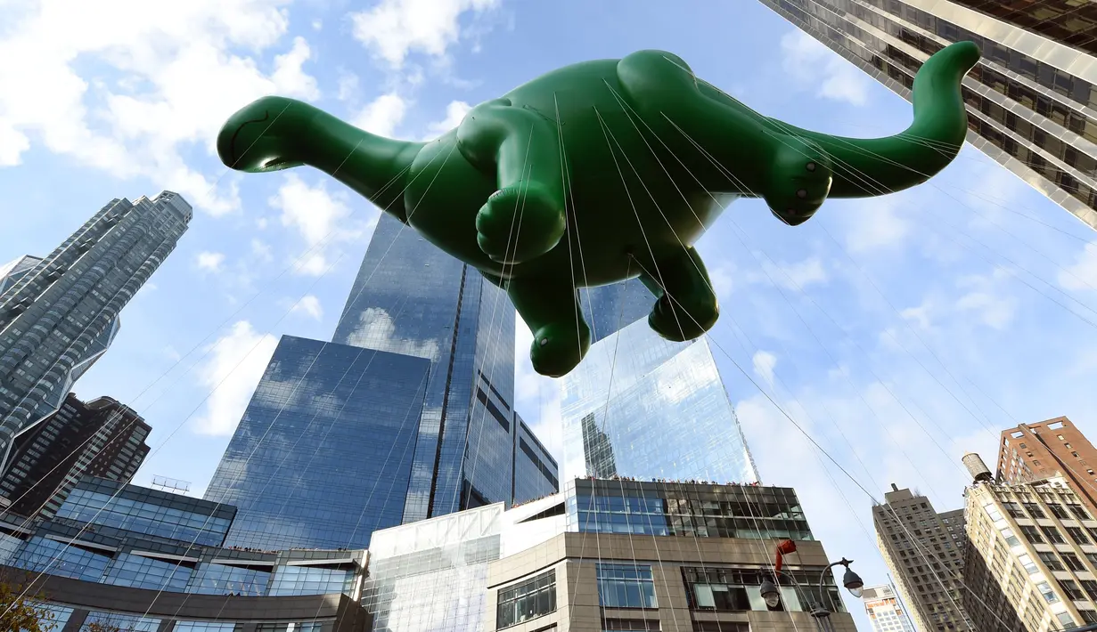 Balon raksaksa berbentuk Dino Saurus ikut meramaikan Parade Thanksgiving Day di New York City (26/11/2015). Beragam balon raksaksa yang dibuat seperti tokoh animasi menjadi suguhan utama dalam perayaan tersebut. (AFP Photo/Timothy A. Clary)