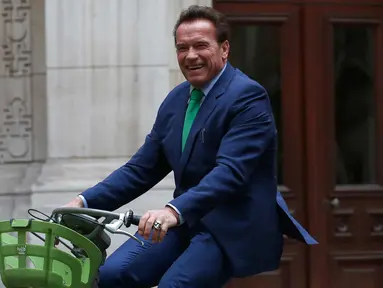 Gubernur California ke-38, Arnold Schwarzenegger tersenyum saat mengendarai sepeda untuk bertemu Walikota Paris, Anne HIdalgo di Paris (11/12). Schwarzenegger berada di Paris untuk menghadiri pertemuan puncak iklim One Planet. (AP Photo / Thibault Camus)