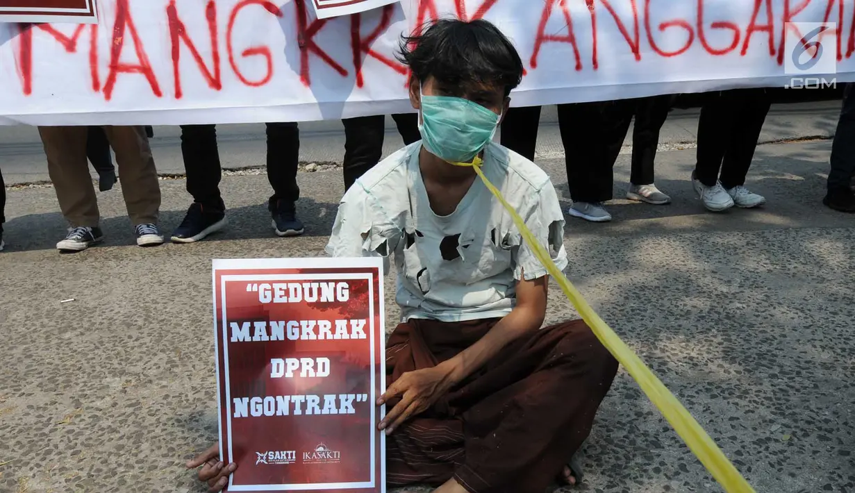 Massa Sekolah Antikorupsi Tangerang dan Ikatan Alumni Sekolah Antikorupsi menggelar aksi di depan Gedung IFA, Tangerang Selatan, Senin (8/10). Massa membawa poster bertuliskan 'Gedung Mangkrak DPRD Ngontrak'. (Merdeka.com/Arie Basuki)
