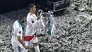 Pemain Real Madrid, Cristiano Ronaldo (kanan) membawa trofi Liga Champions 2017/2018 bersama rekannya Karim Benzema saat merayakan kemenangan di Stadion Santiago Bernabeu, 27 Mei 2018. (AFP/Gabriel Bouys)