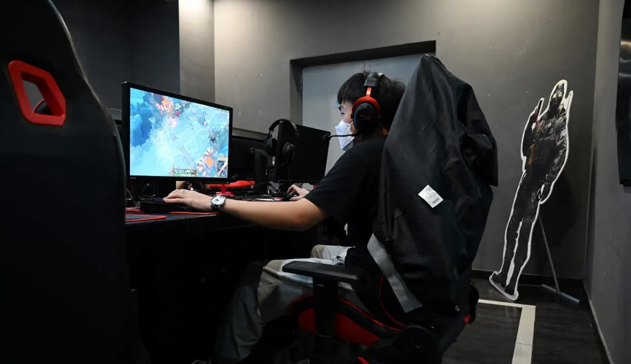 Seorang pria bermain game komputer di sebuah kafe internet di Beijing, China, Jumat (10/9/2021). Tidak semua orang menyetujui pembatasan bermain game online di China. (GREG BAKER/AFP)