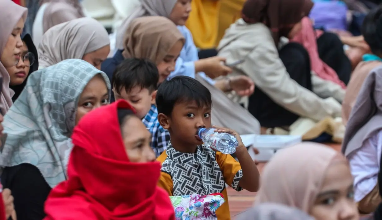 Seorang anak kecil sedang meminum air mineral saat momen buka puasa di Masjid Istiqlal. (Foto: Istimewa)
