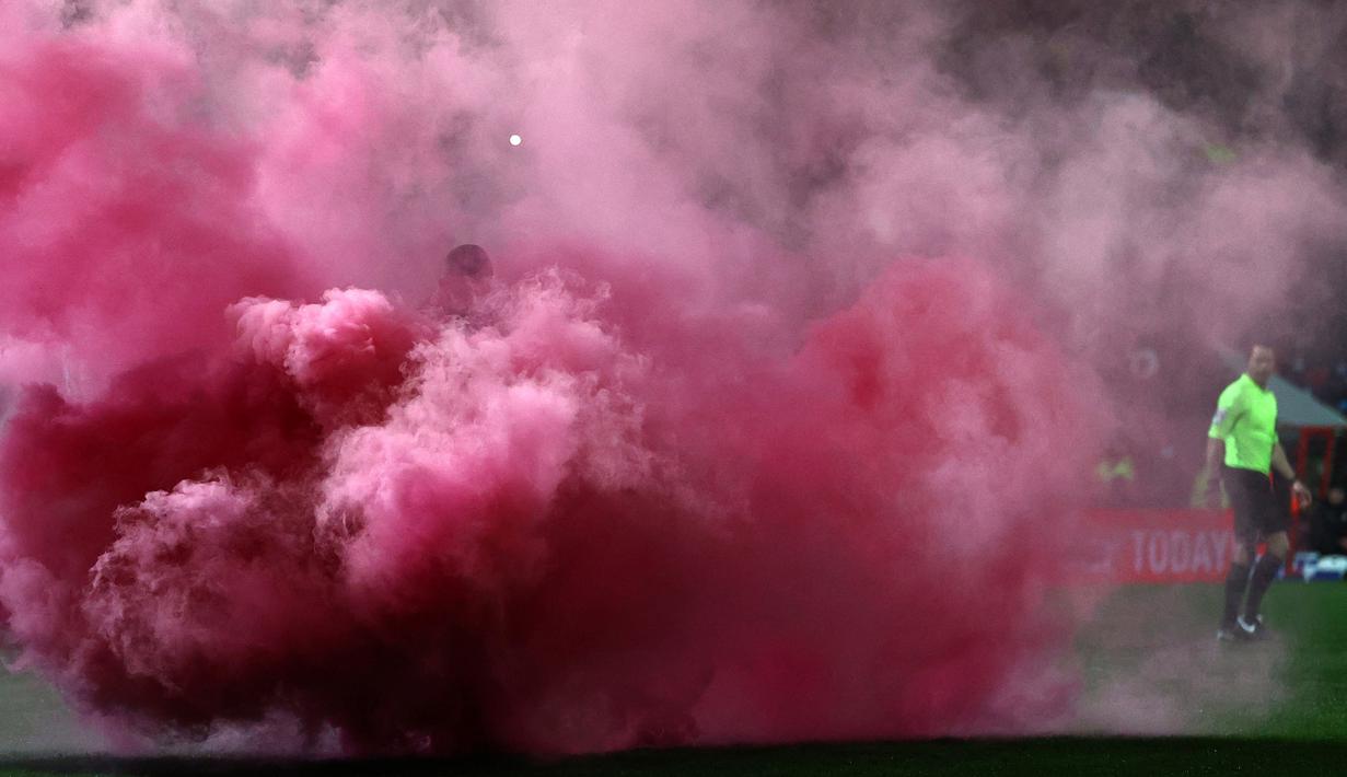 Laga Swindon Town kontra Manchester City pada putaran ketiga Piala FA 2021/22 yang berlangsung di Country Ground diwarnai dengan smoke bomb. Hal tersebut terjadi saat Harry McKirdy mencetak gol pertama dan satu-satunya untuk The Robins. (AFP/Adrian Dennis)