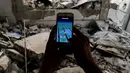 Daerah konflik di Suriah yang penuh dengan puing dan reruntuhan bangunan dijadikan tempat untuk bermain Pokemon Go oleh seorang gamer Suriah, Damaskus (23/7). (AFP PHOTO / Sameer Al-Doumy)