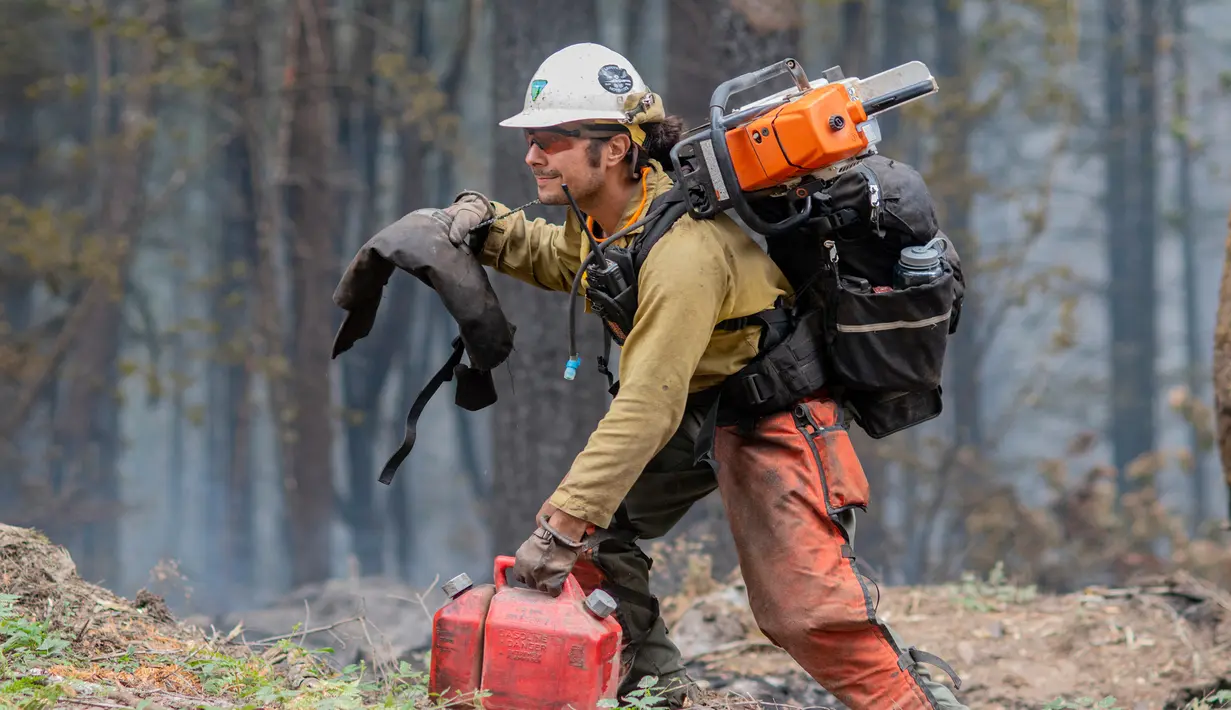 <p>Seorang petugas pemadam kebakaran bekerja untuk menahan api Cedar Creek di sebelah timur Oakridge, Oregon, Senin (12/9/2022). Kebakaran menghabiskan lahan setara dengan dua kali ukuran Ibu Kota AS, Washington. (Photo by Dan Morrison/AFP)</p>