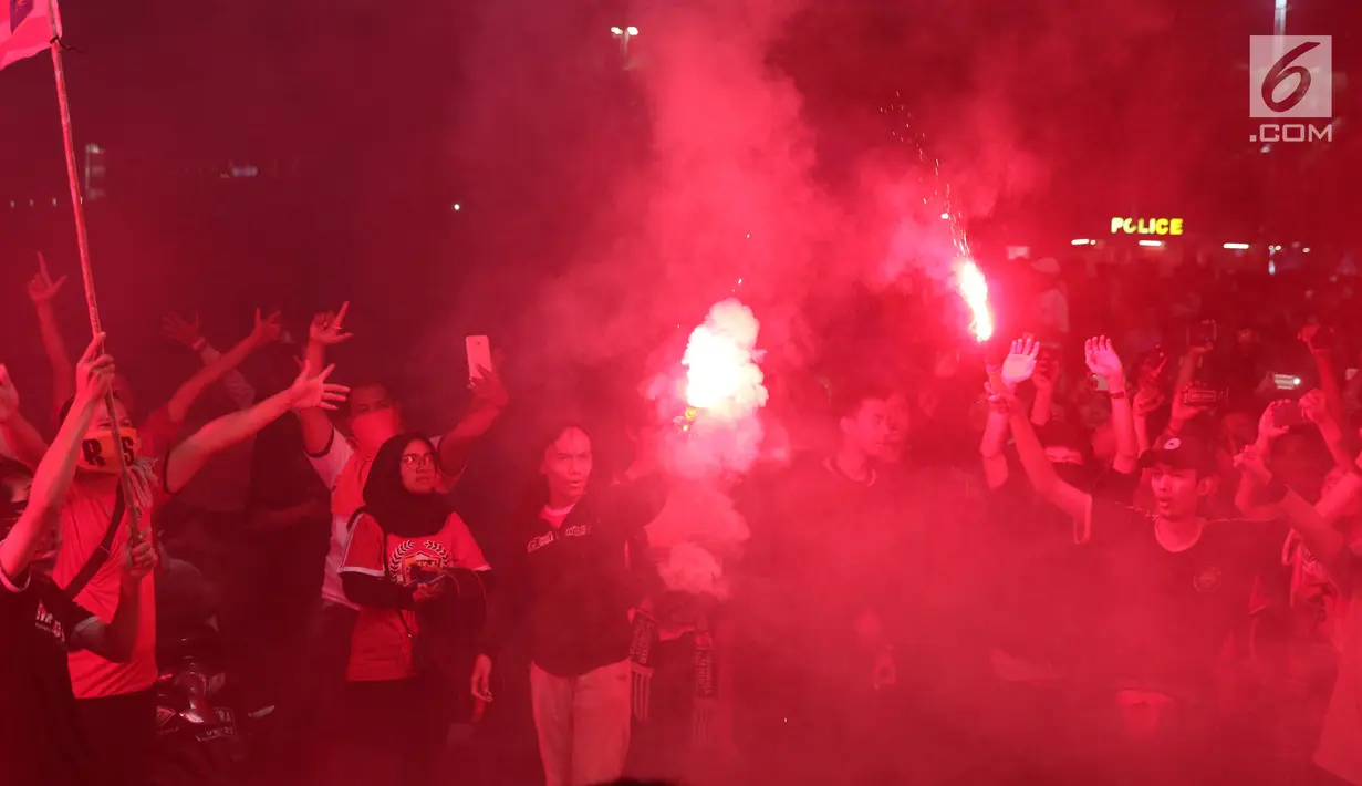 Suporter tim Macan Kemayoran menyalakan flare saat merayakan gelar juara Go-Jek Liga 1 Indonesia 2018 bersama Bukalapak yang diraih Persija di kawasan Bundaran HI, Jakarta, Minggu (9/12). Persija juara dengan 62 poin. (Liputan6.com/Helmi Fithriansyah)