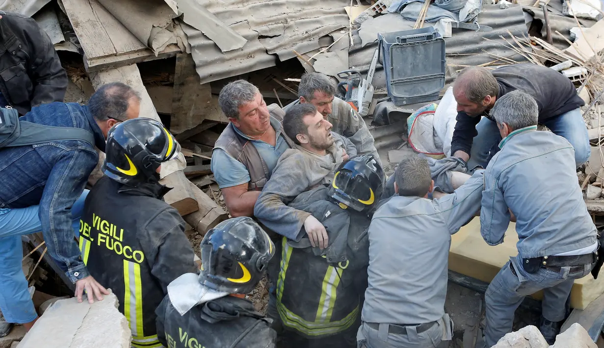 Petugas dibantu warga saat berhasil mengeluarkan seorang pria yang tertimbun reruntuhan bangunan akibat gempa di Amatrice, Italia tengah, (24/8). Gempa dengan kekuatan 6,2 SR ini membuat warga panik. (REUTERS/Remo Casilli)