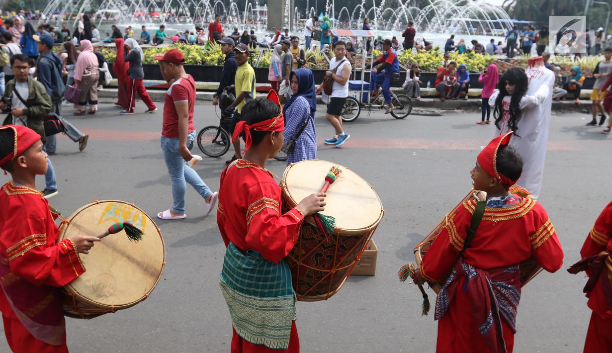 Seniman cilik memainkan alat musik tambur khas Minangkabau saat car free day (CFD) di Jakarta, Minggu (13/1). Pertunjukan ini juga sekaligus untuk mengenalkan keberagaman budaya Nusantara. (Liputan6.com/Angga Yuniar)