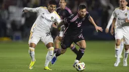 Pemain Inter Miami, Lionel Messi (kanan) berebut bola dengan pemain LA Galaxy, Edwin Cerrillo pada laga Major League Soccer 2024 di Dignity Health Sports Park, California, Amerika Serikat, Senin (26/02/2024) WIB. (AP Photo/Kyusung Gong)