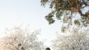 Sentuhan couture semakin terasa lewat detail panel pleated pada bagian samping rok yang menyerupai kelopak bunga raksasa. Elemen ini memberikan dimensi unik yang membuat gaun Jennifer tampil berbeda dari wedding gown klasik pada umumnya. [@jennifercoppenreal20].