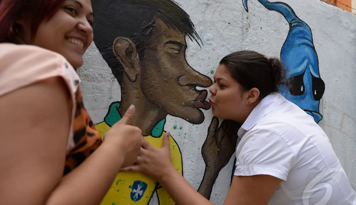Dua orang wanita tampak berpose dengan karikatur Neymar, kota Rio de Janeiro, Jumat (9/5/2014) (AFP PHOTO / Vanderlei Almeida).