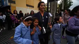Sejumlah anak dievakuasi dari dalam gedung saat terjadi gempa di Vina del Mar, Chile (24/4). Pemerintah Chile menghimbau warga menyelamatkan diri ke tempat lebih tinggi dan menjauhi pantai. (AFP Photo/Francesco Degasperi)