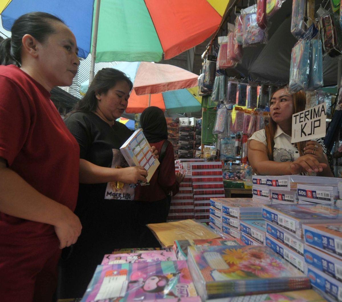 Pedagang menawarkan perlengkapan alat tulis sekolah kepada calon pembeli di Pasar Asemka, Jakarta (4/7/2024). Memasuki tahun ajaran baru sekolah, buku tulis mulai laris manis diserbu orang tua murid. Foto: merdeka.com / Imam Buhori