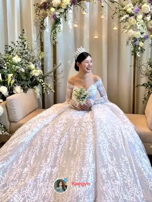 Saat mengikat janji suci, Lee Da In tampil cantik dalam balutan princess gown yang megah. Off-the-shoulder gown ini memiliki detail bagian dada berbentuk hati dan rok yang megah berhias brokat dedaunan. Lee Da In juga menambahkan tiara dan kudung transparan, menyempurnakan penampilannya sebagai pengantin. Foto: Instagram.