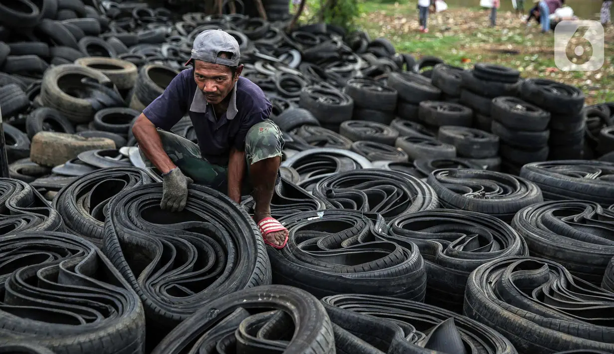 Pekerja mengumpulkan ban mobil bekas di kawasan Petamburan, Jakarta, Minggu (12/12/2021). Keterbatasan lahan membuat para pengepul terpaksa mengumpulkan limbah ban bekas dari seluruh kawasan bantaran Kanal Banjir Barat. (Liputan6.com/Faizal Fanani)