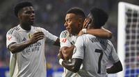 Kylian Mbappe dari Real Madrid (tengah) mendapat ucapan selamat dari rekan-rekannya, Vinicius Junior (kanan) dan Aurelien Tchouameni, setelah mencetak gol dalam laga La Liga antara Real Oviedo dan Real Madrid di Stadion Carlos Tartiere, Oviedo, Spanyol, Minggu, 24 Agustus 2025. (AP Photo/Miguel Oses)