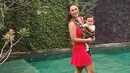 Kalau yang satu ini, Alexandra berada di tepi kolam renang sambil menggendong anaknya. Ia juga tetap seksi dengan mini dress merah dan sangat memerlihatkan lekuk tubuhnya yang seksi. (Instagram/got_alex)