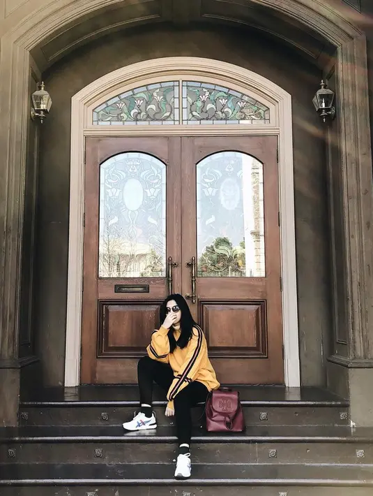 Paduan celana htam, sweater kuning dan sneakers putih pas banget dikenakan oleh Isyana. Gayanya makin kece dan hits lantaran ia mengenakan kacamata hitamnya. (Instagram/isyanasarasvati)