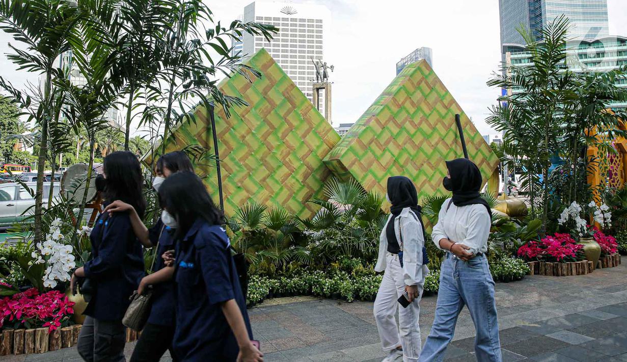 <p>Sejumlah warga berjalan melewati dekorasi bertemakan Idul Fitri di kawasan Bundaran HI, Jakarta, Rabu (27/4/2022). Dekorasi berbentuk masjid, ketupat, dan bedug yang dihiasi oleh tanaman tersebut dalam rangka menyambut Idul Fitri 1443 Hijriah. (Liputan6.com/Faizal Fanani)</p>