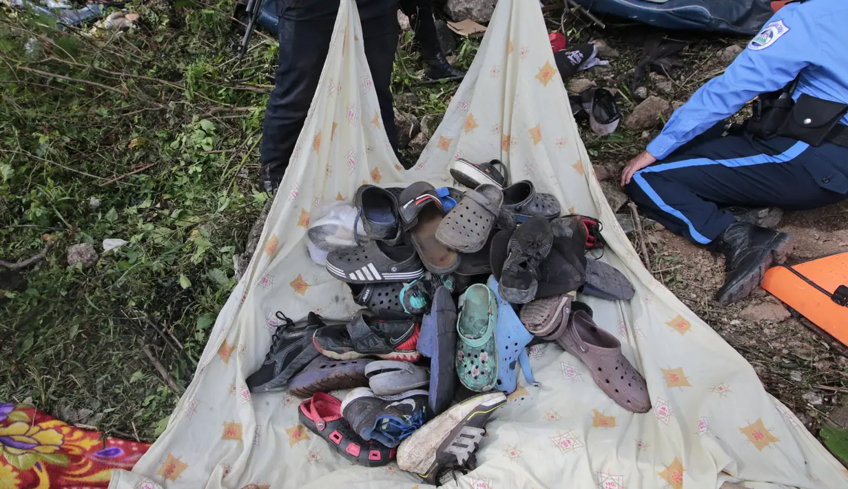 Seorang petugas polisi mengumpulkan sepatu dari bus yang jatuh di jalan raya Pan-Amerika di Condega, Nikaragua (28/7/2022). Polisi melaporkan pada Kamis (28/7) Kecelakaan lalu lintas yang terjadi di jalan raya di Nikaragua utara menyebabkan 16 orang tewas, termasuk 13 orang Venezuela, mungkin migran, selain 47 terluka. (AFP Photo/ Oswaldo Rivas)