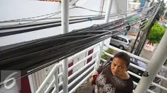Warga melintas di bawah instalasi kabel yang menjuntai di JPO kawasan Cawang, Jakarta, Rabu (25/1). Selain mengganggu kenyamanan, buruknya penempatan instalasi kabel tersebut juga berbahaya bagi keselamatan pengguna JPO. (Liputan6.com/Immanuel Antonius)