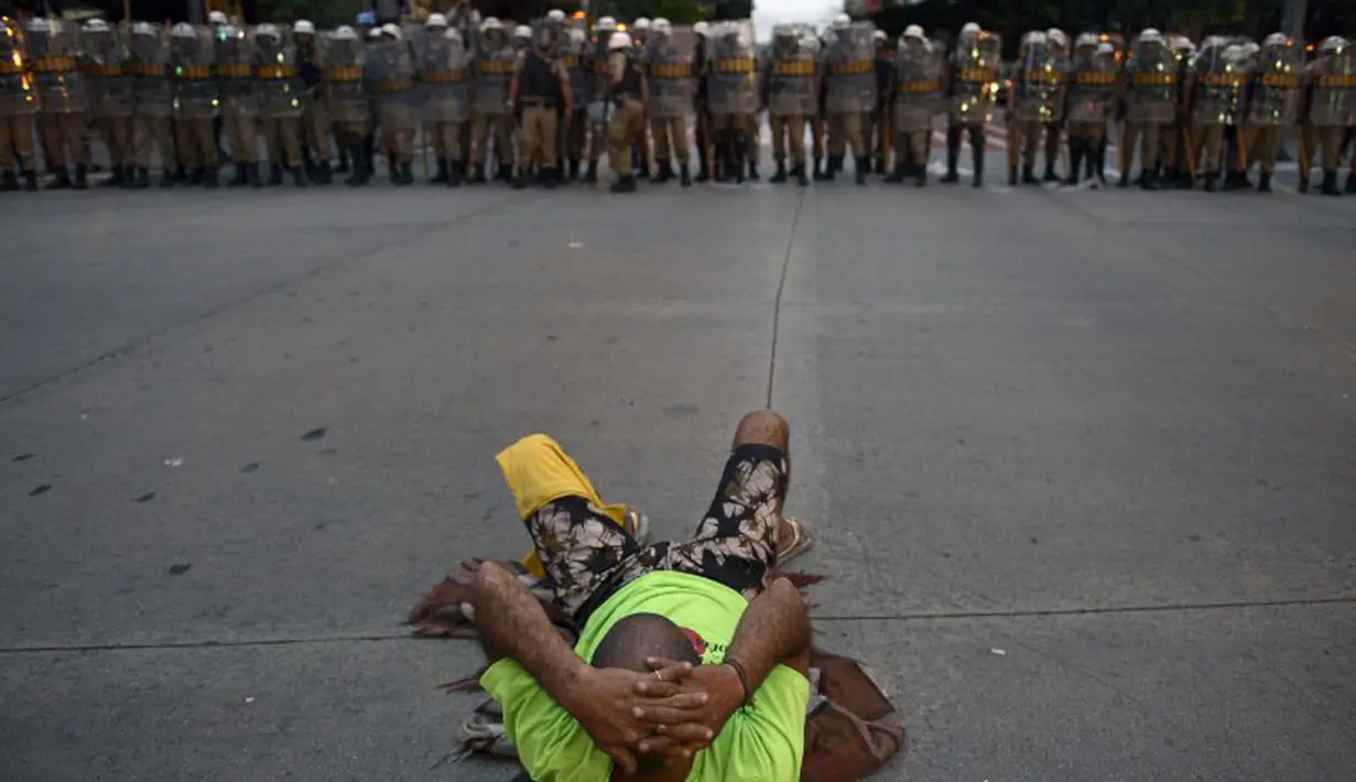Di Belo Horizonte, Brasil, seorang pengunjuk rasa melakukan aksi dengan telentang di depan pasukan polisi anti huru hara, (12/6/2014). (AFP PHOTO/Juan Mabromata)